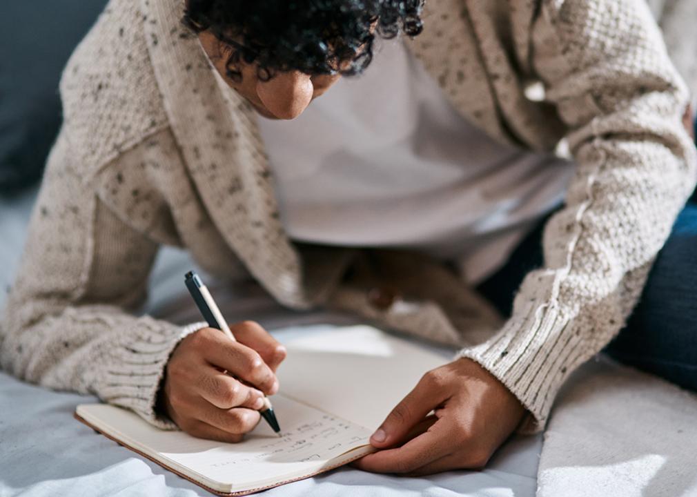 A young man writing on a journal.