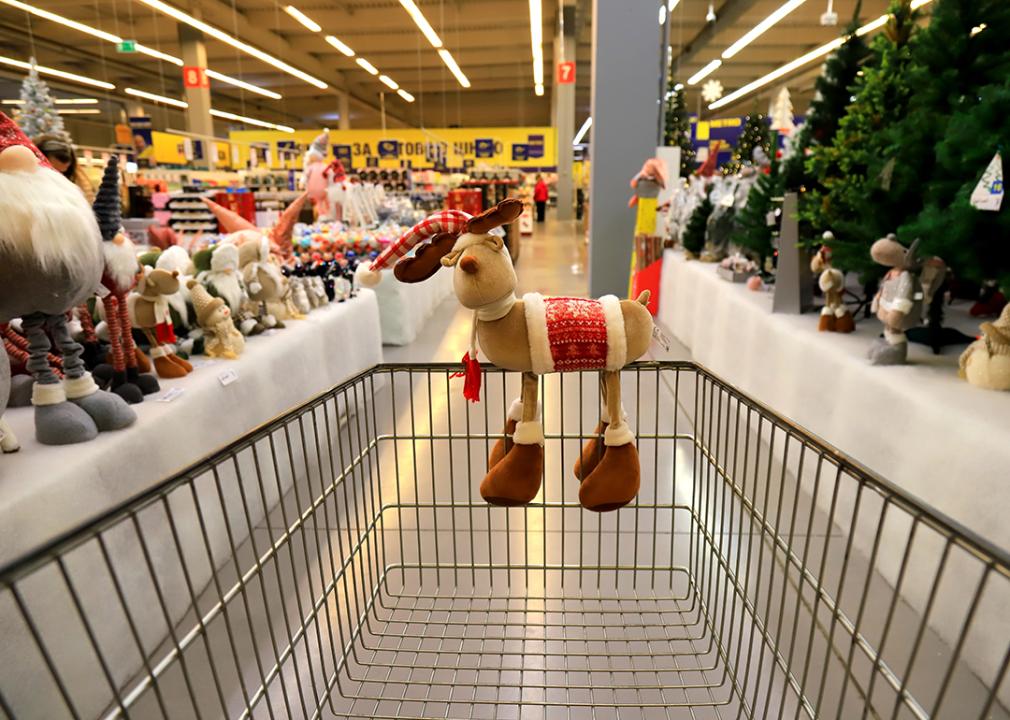 A Christmas deer on a supermarket cart facing the Christmas wholesale aisle.