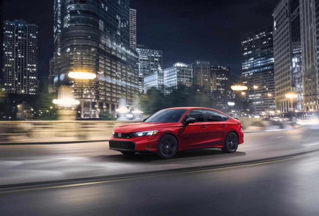 A red Honda Civic driving by a blurred cityscape.