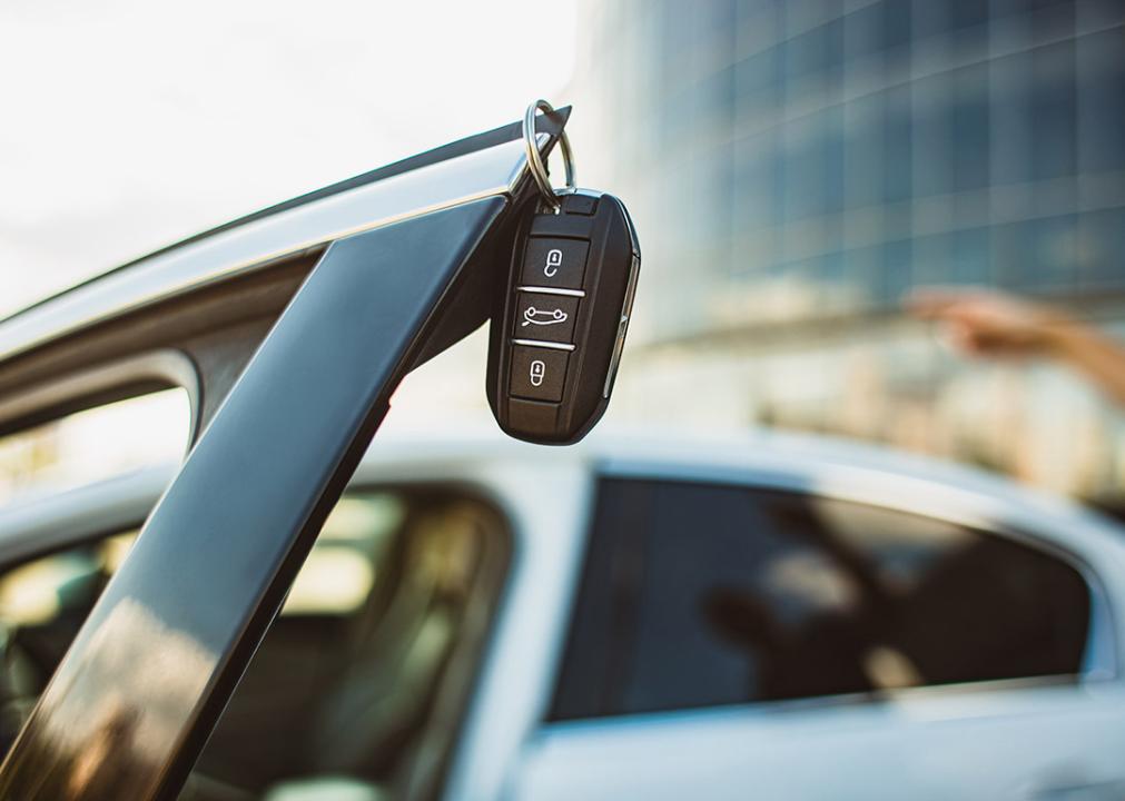 A leased car's key hanging on the edge of an open vehicle door.