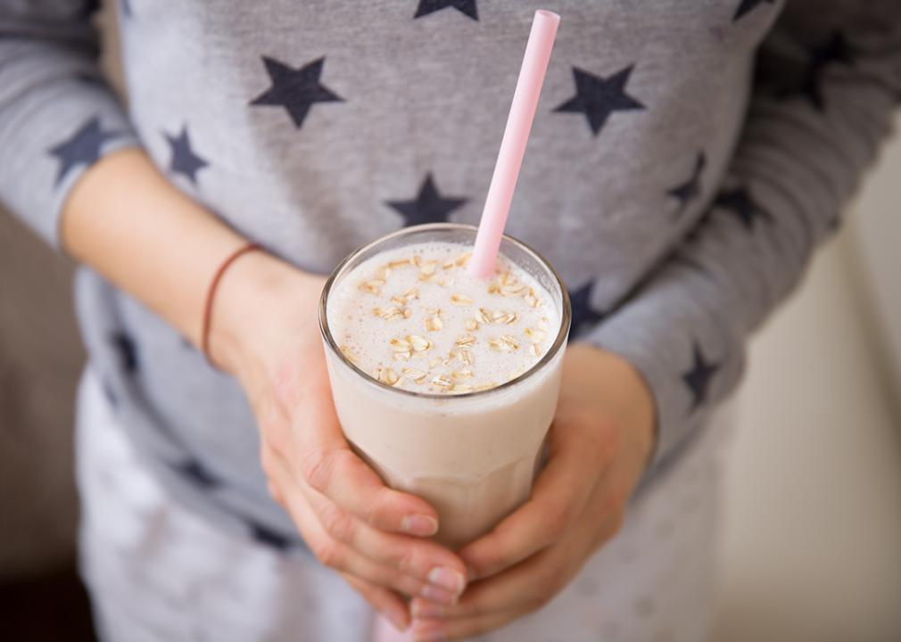 A woman holding a glass of blended oats drink. Oatzempic is one of the viral weight loss hack trends of the past year.