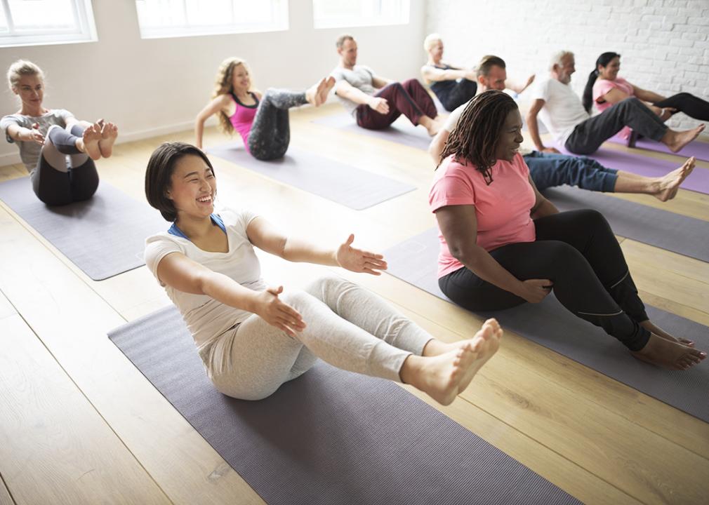 A group of diverse adult women and men in a yoga/exercise class.