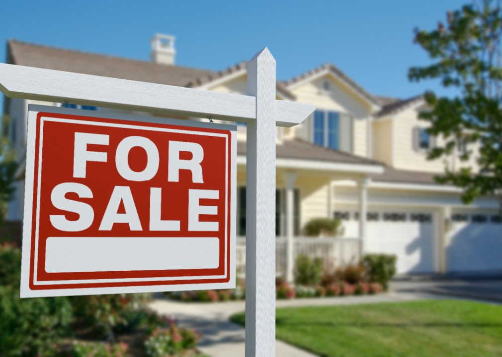 Red for sale sign in front of two-story house.