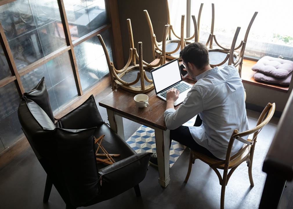 A small business owner closed up shop and looks up information on a laptop.