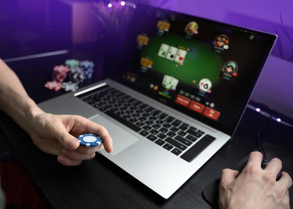 A young man playing online poker using a laptop.