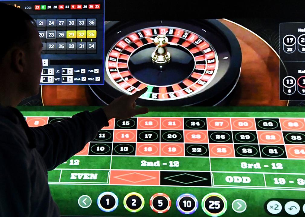 A man stands and points at a huge screen showing internet casino.