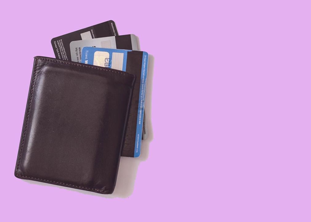 Overhead view of wallet with multiple credit cards spilling out against a pink backdrop.