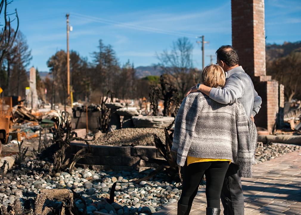 A couple looks at the ruins of their owned home caused by a fire disaster.