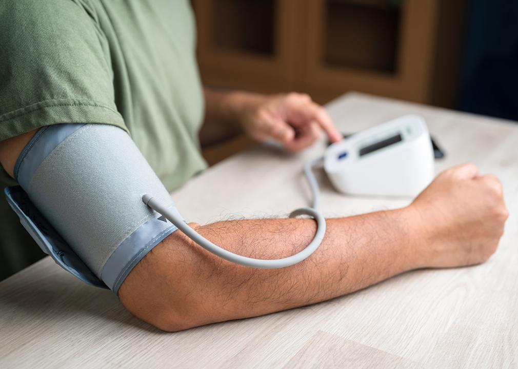 Young man getting his blood pressure checked at home with a digital monitor.