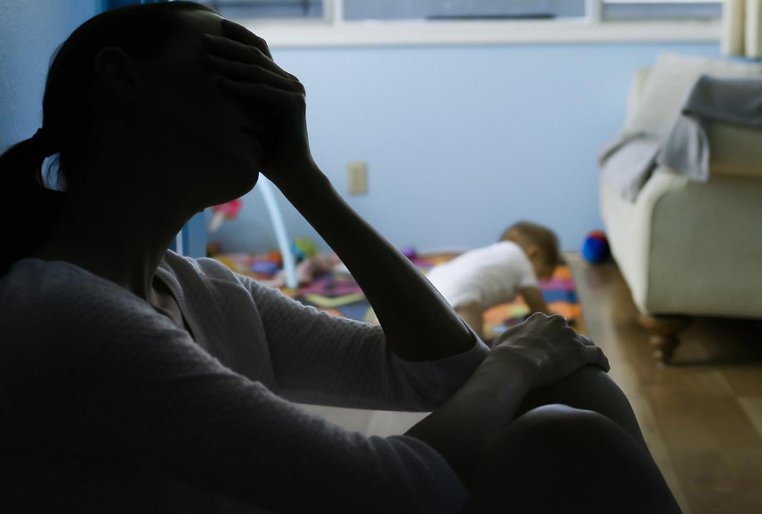 Silhouette of a stressed mother sitting at the corner of her baby's room.