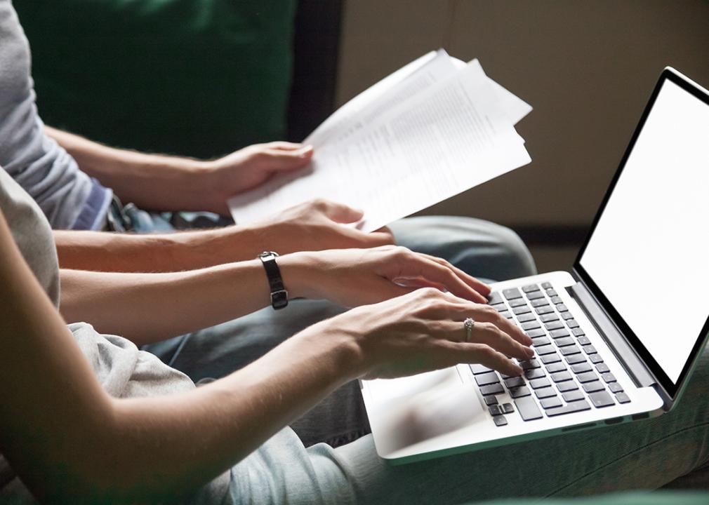 Young adults organizing finances such as student loan documents using a laptop.