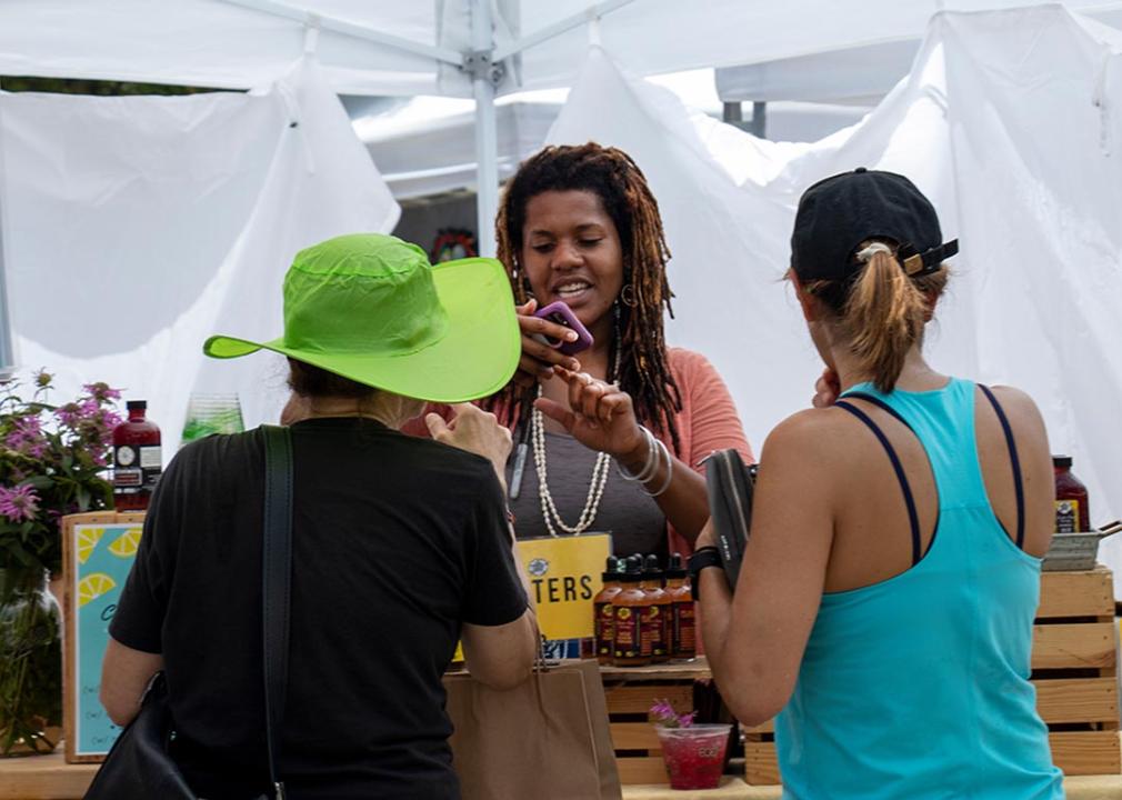 A vendor in the artist market area takes a mobile payment from a customer during the AthFest music and arts festival.