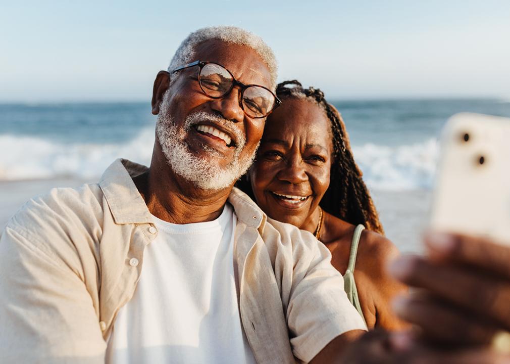 Older couple sharing a happy moment by taking selfies at the beach.