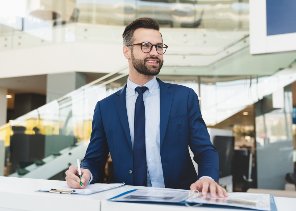 A man in a suit smiling while standing at reception desk.