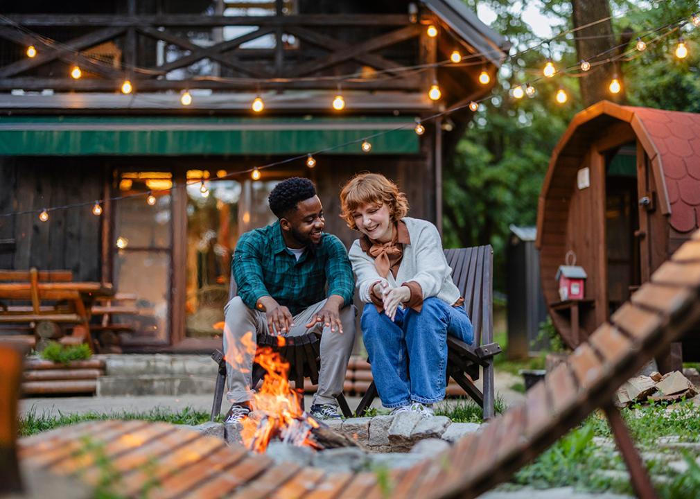 A multiracial couple having quality time by a campfire outdoors.