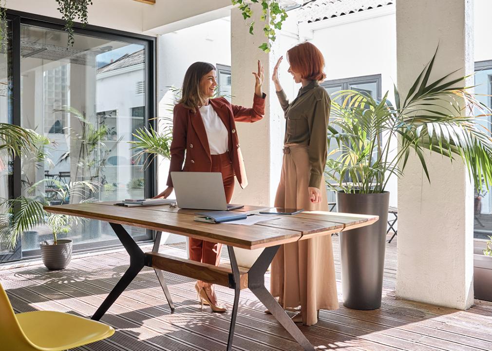 Two happy women entrepreneurs celebrating work success.