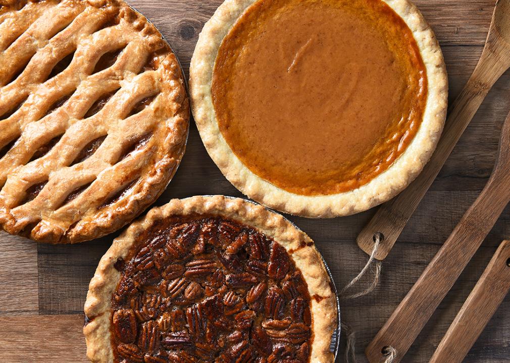 Apple, pumpkin and pecan pies on a wooden table.