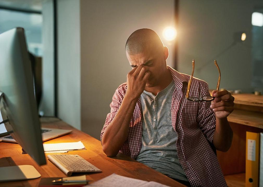 Stressed out man in front of his computer massaging forehead.