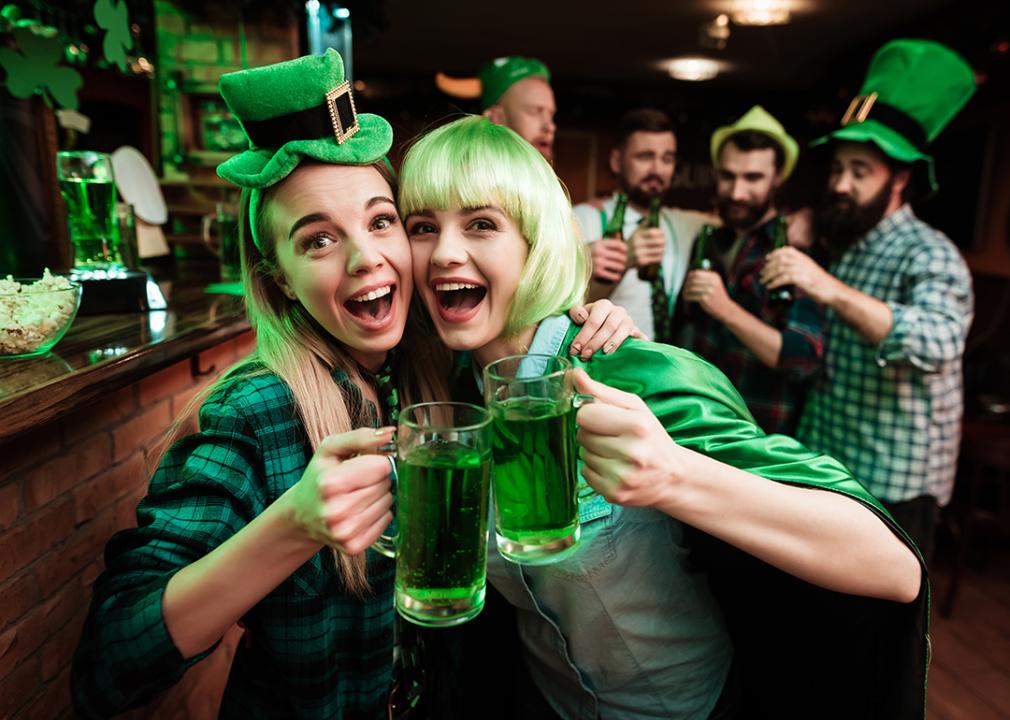 Two girls in a wig and a cap celebrating St. Patrick's Day in a bar.