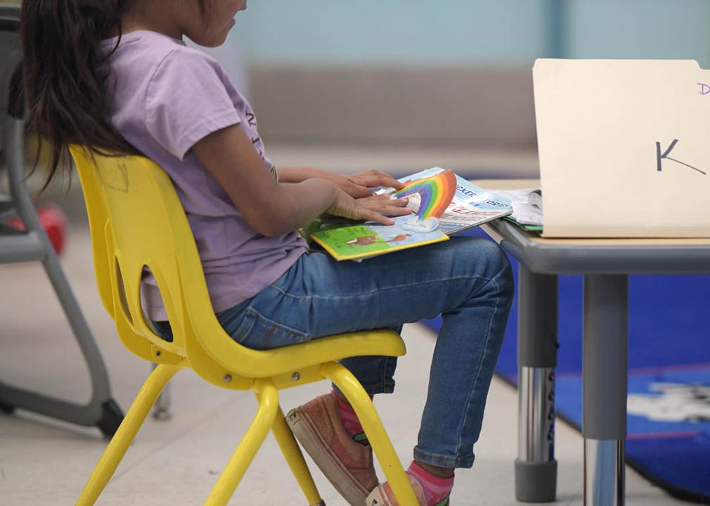 A young girl enrolled in Havasupai Elementary school is sitting inside a classroom reading a children