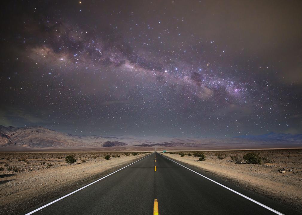 A starry night sky and road lines in a death valley desert in California, USA.