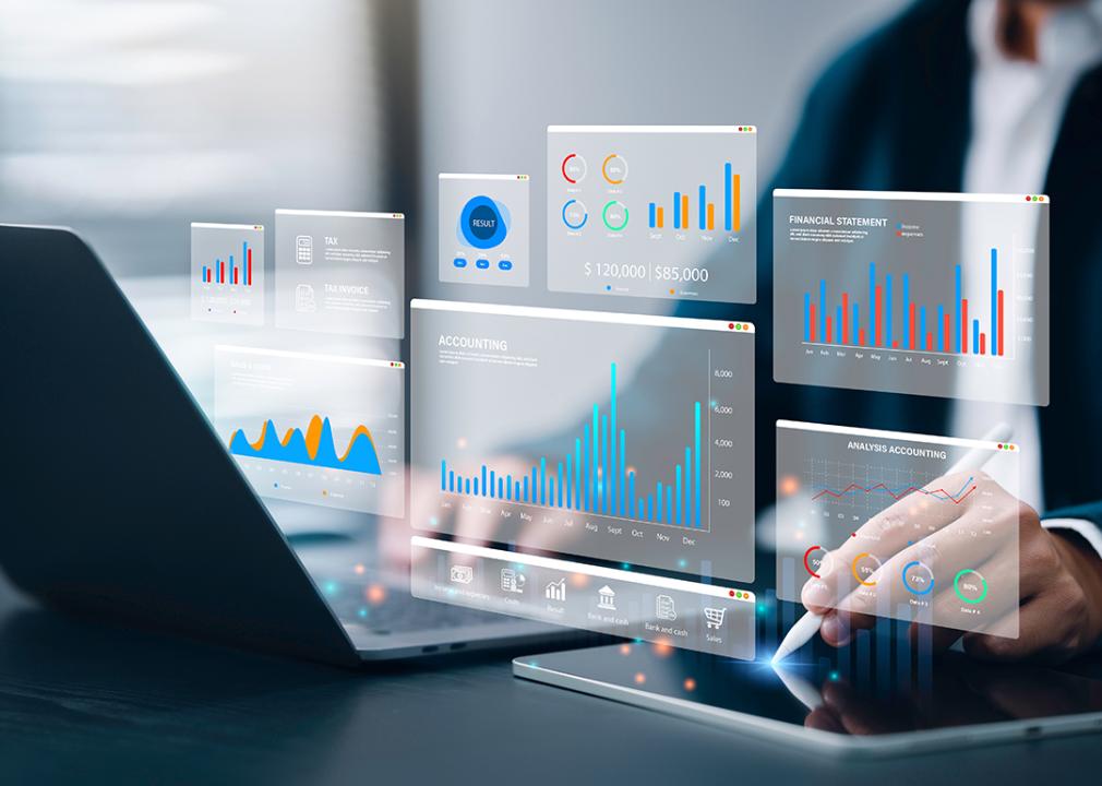 Accountant using a laptop and digital tablet with holographic visualizations of an accounting software.