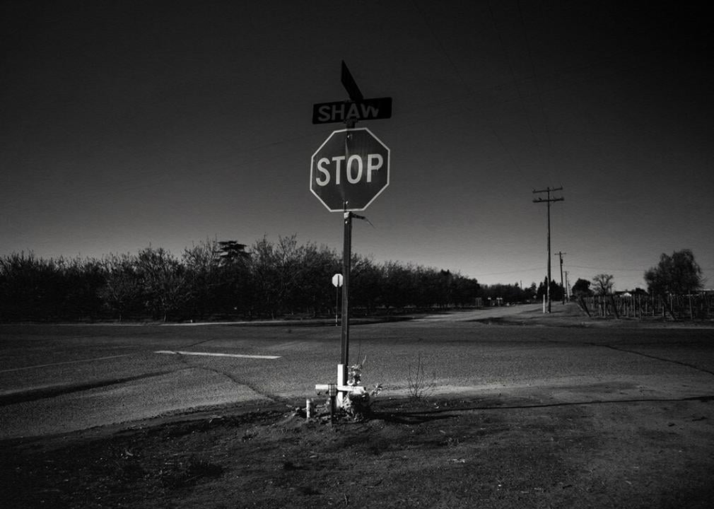 A black and white photo of a stop sign in the middle of an empty intersection.