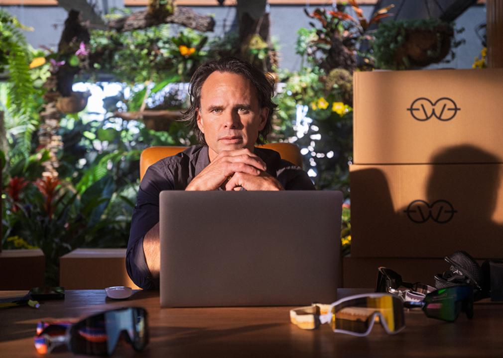 Actor Walton Goggins posed in front of a workspace and a laptop.