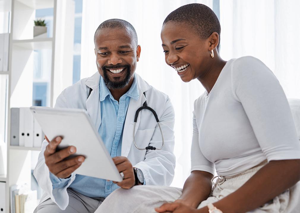 Female employee availing healthcare benefits happily consulting with a doctor.