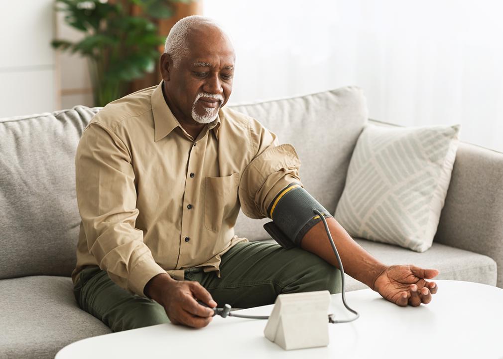 A senior black man measuring his blood pressure using a digital monitor.