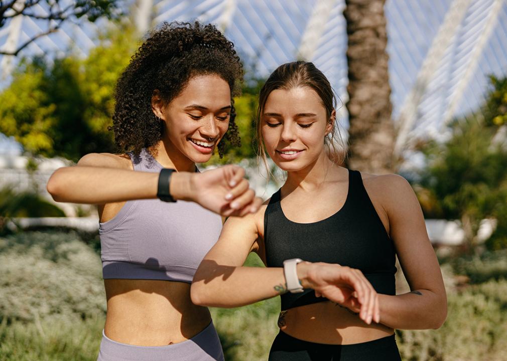 Two young women checking health data on their smartwatches.