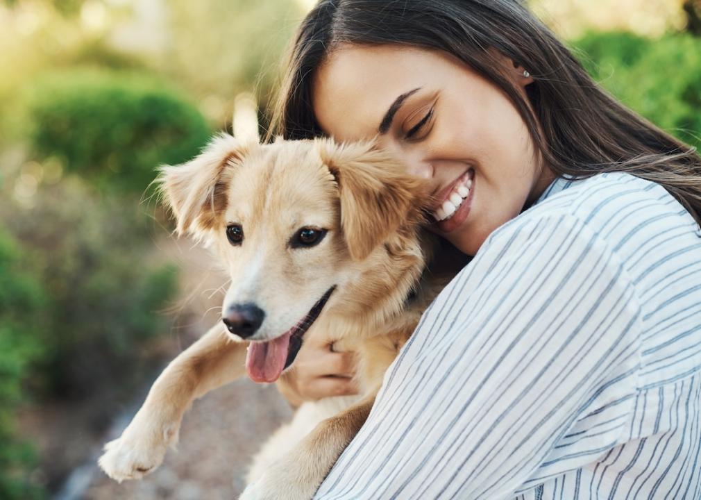 Woman smiling while holding her pet dog.