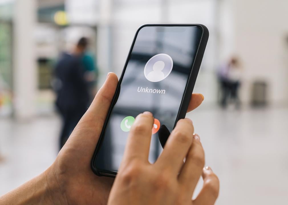 Person holding their phone with an incoming call from an unknown number.