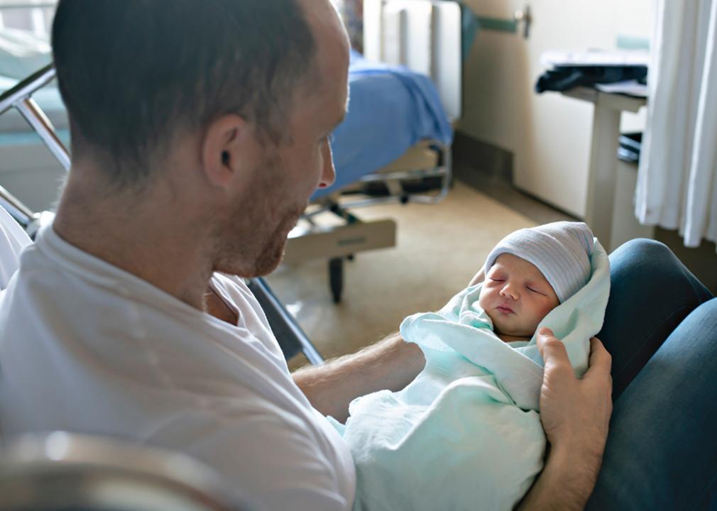 A father holding his newborn baby at the hospital a day after birth.