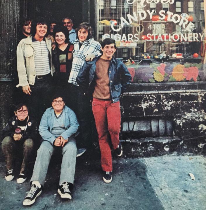 Some kids hanging outside Rose's Candy Store in East Harlem, New York. 1973. A group of kids stand and sit in front of a candy store
