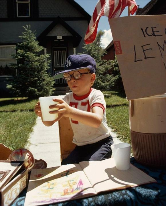 A boy at his front yard lemonade stand in 1973 A boy wearing a Dodgers ball cap selling lemonade in his front yard