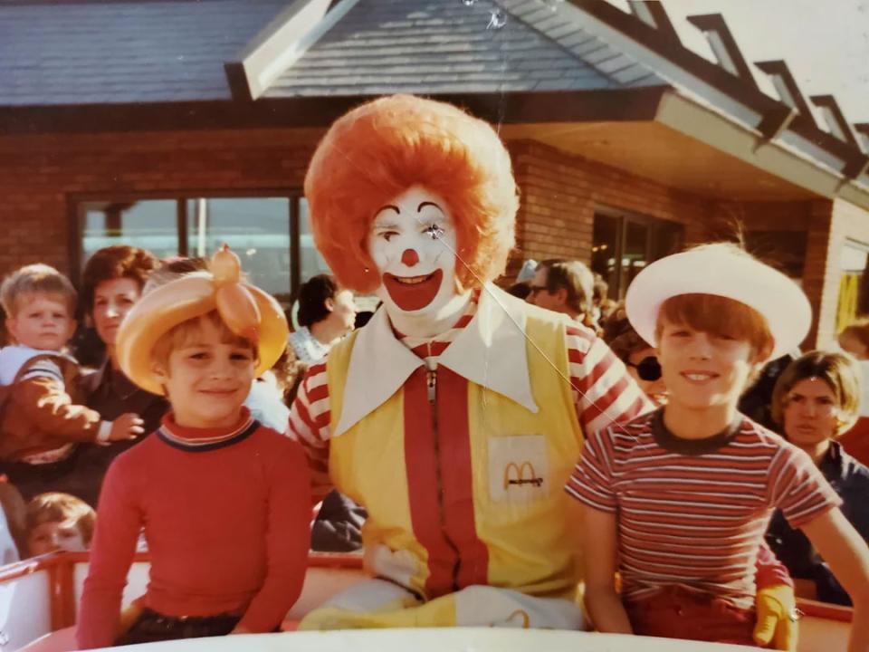 "My dad and uncle in Warren, Ohio at a McDonald's grand opening. October, 1973." Two boys sitting on either side of a man dressed as Ronald McDonald