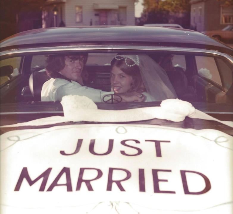 "My parents in 1973. They're still together and celebrated their 50th anniversary 3 years ago." A couple inside a car looking through the back window at the camera. Just Married is painted on the trunk.