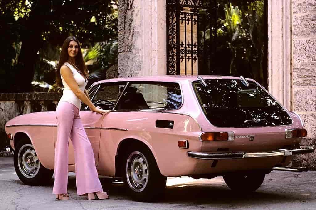 Women in pink bell bottoms stands next to her pink car