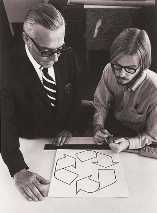 Gary Dean Anderson with his winning submission to the "design a recycling logo" contest of 1973 Gary Dean Anderson holding a pen looking at his design