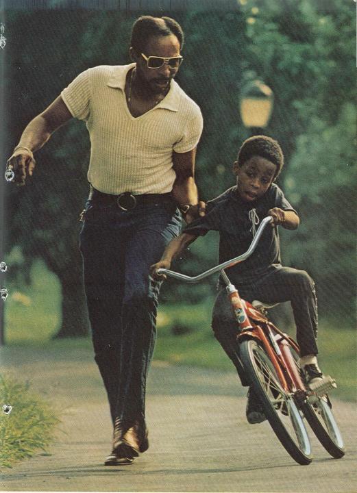 Dad teaching his son to ride a bike in Central Park, New York Father holding onto his sons arm as he learns how to ride a bike