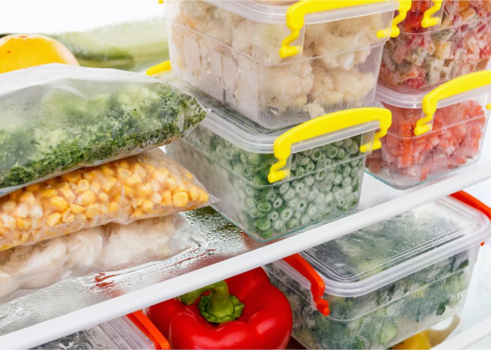 Photo shows vegetables and other food items arranged in plastic storage containers inside a fridge