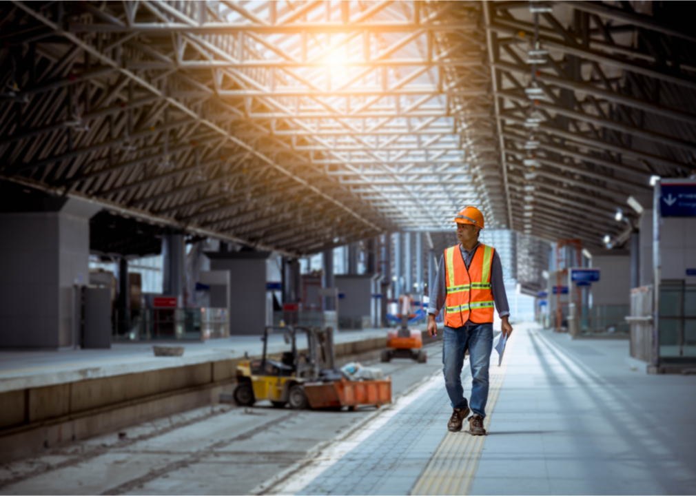 A rail worker walks on rail station platform.