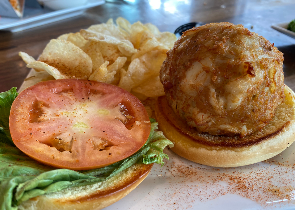 Deep fried crab cake sandwich on bun with lettuce and tomato.
