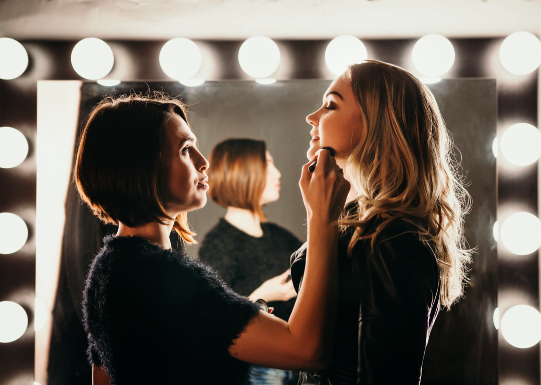 Makeup artist prepares actress for stage.
