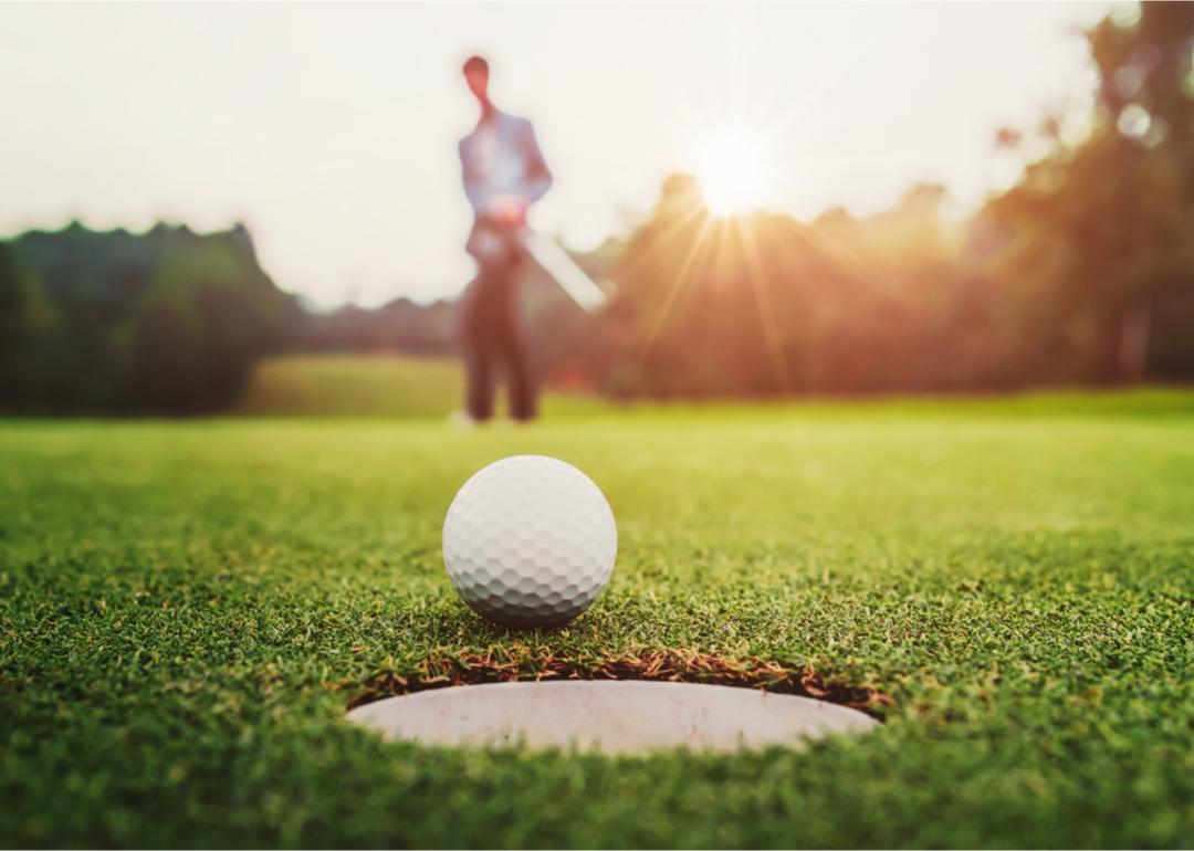A close-up view of a golfer hitting a golf ball into a hole.