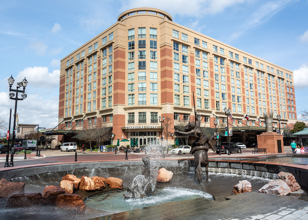 View of Sugar Land Town Square, with fountain, sculptures, and building.