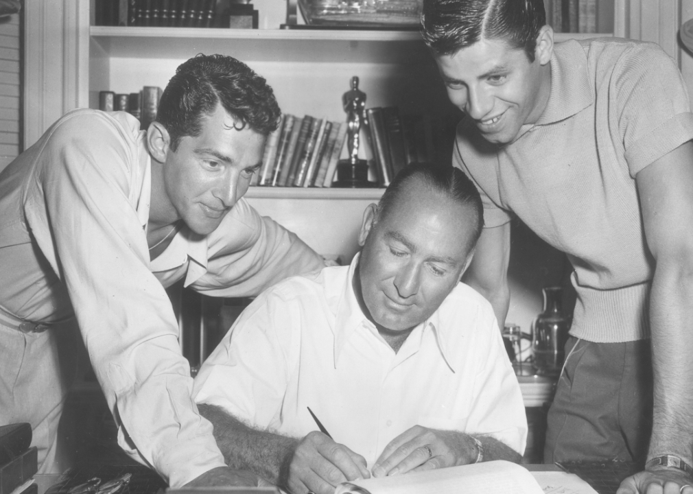 Hal B Wallis  sits at his desk with Dean Martin and Jerry Lewis.