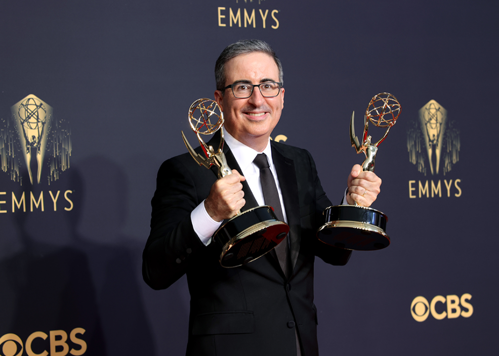 John Oliver poses in the press room with Emmy Awards.