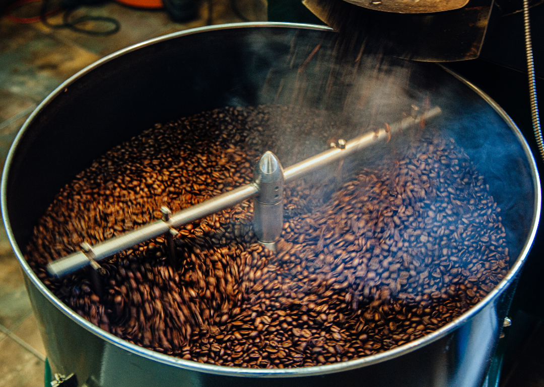 Roaster pouring freshly roasted coffee into cooling tray.